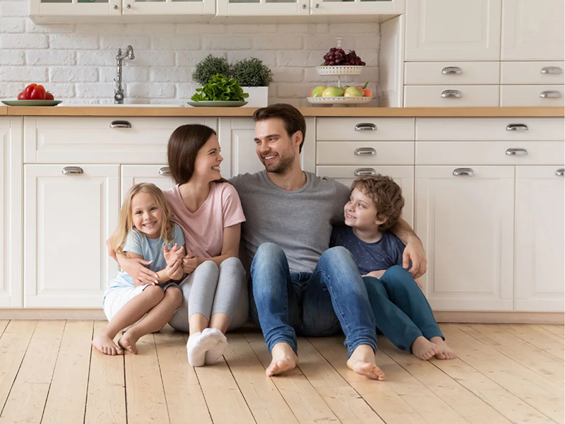 Happy family sitting together on hardwood flooring