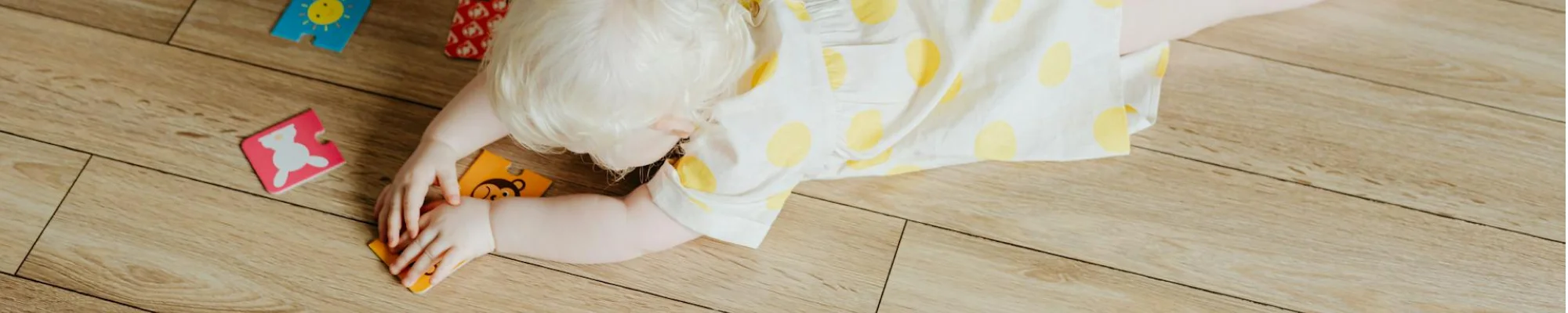 Woman watching toddler laying down, playing on durable hardwood flooring